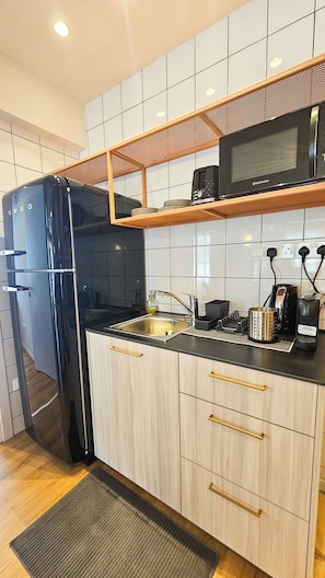 A modern kitchen with a black refrigerator, wooden cabinets, a microwave, and a sink. - The Colors of Larnaca (Larnaca)