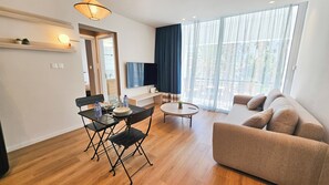A modern living room with a dining area, a sofa, a TV, and a balcony with curtains. - The Colors of Larnaca (Larnaca)