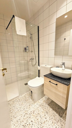 A modern bathroom with a glass-enclosed shower, a toilet, a sink, and a vanity with a mirror. - The Colors of Larnaca (Larnaca)