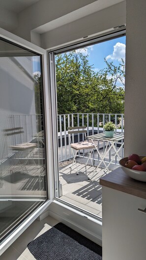 Ein Balkon mit Tisch, Stühlen, einer Topfpflanze und einer Obstschale.