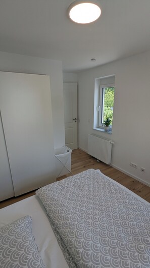 Une chambre à coucher avec un lit, une fenêtre, un radiateur et une porte.