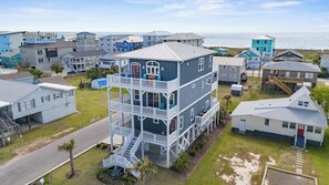 Un immeuble résidentiel à plusieurs étages, doté d’un balcon, d’un escalier et offrant une vue sur l’océan.