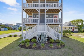 A multi-story building with a central staircase, balconies, and a small garden area. - The Caddyshack at Carolina Beach (Carolina Beach)