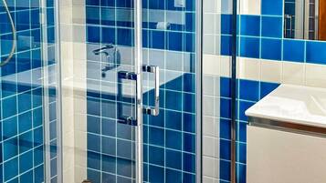 Ein Badezimmer mit blauen Fliesen, einer Duschkabine aus Glas und einem weißen Waschbecken.