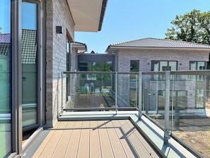 Ein modernes Gebäude mit einer Holzterrasse, großen Fenstern und einer Ziegel-Fassade.