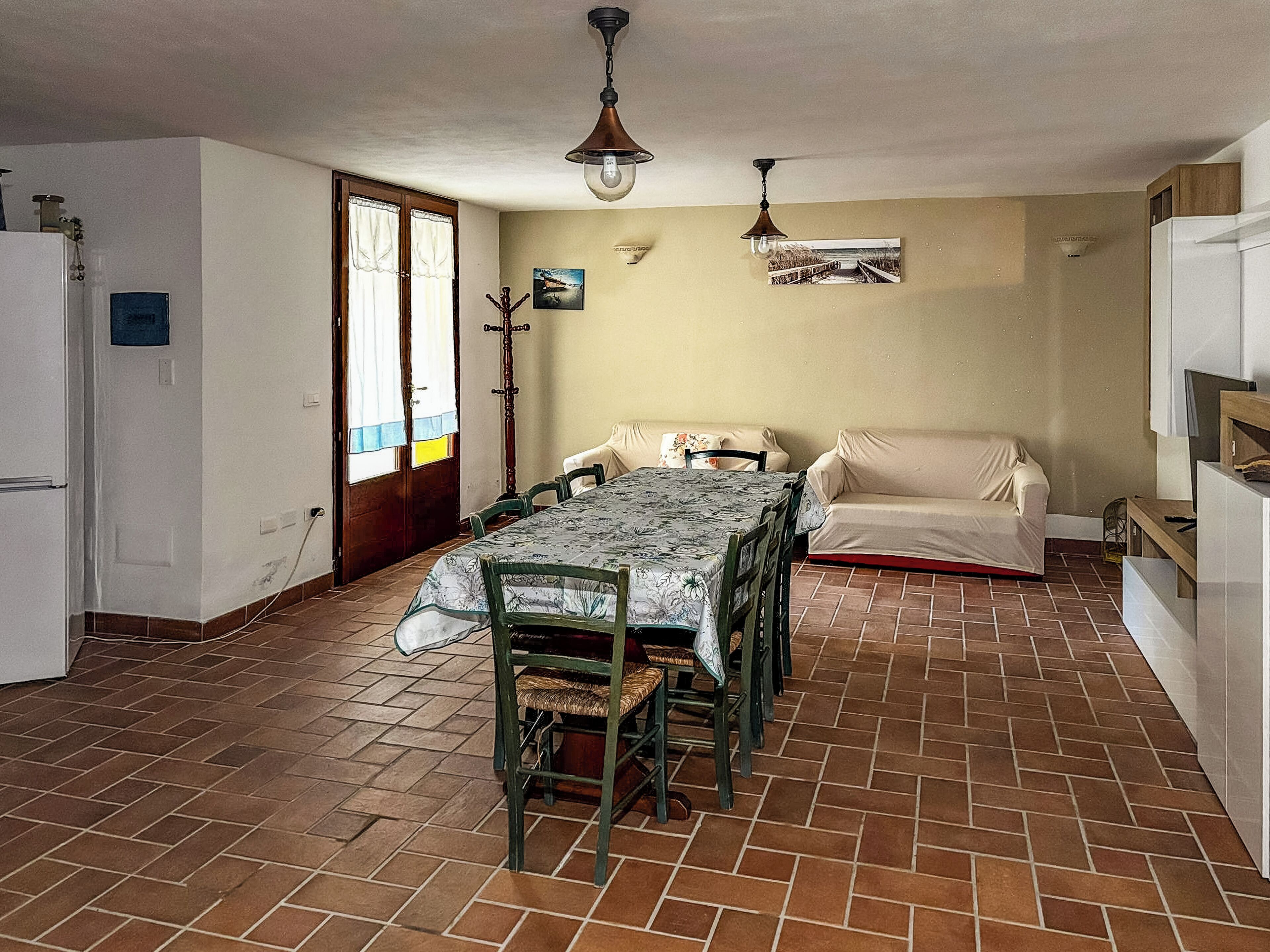 Un comedor con una mesa, sillas, un sofá y un refrigerador.