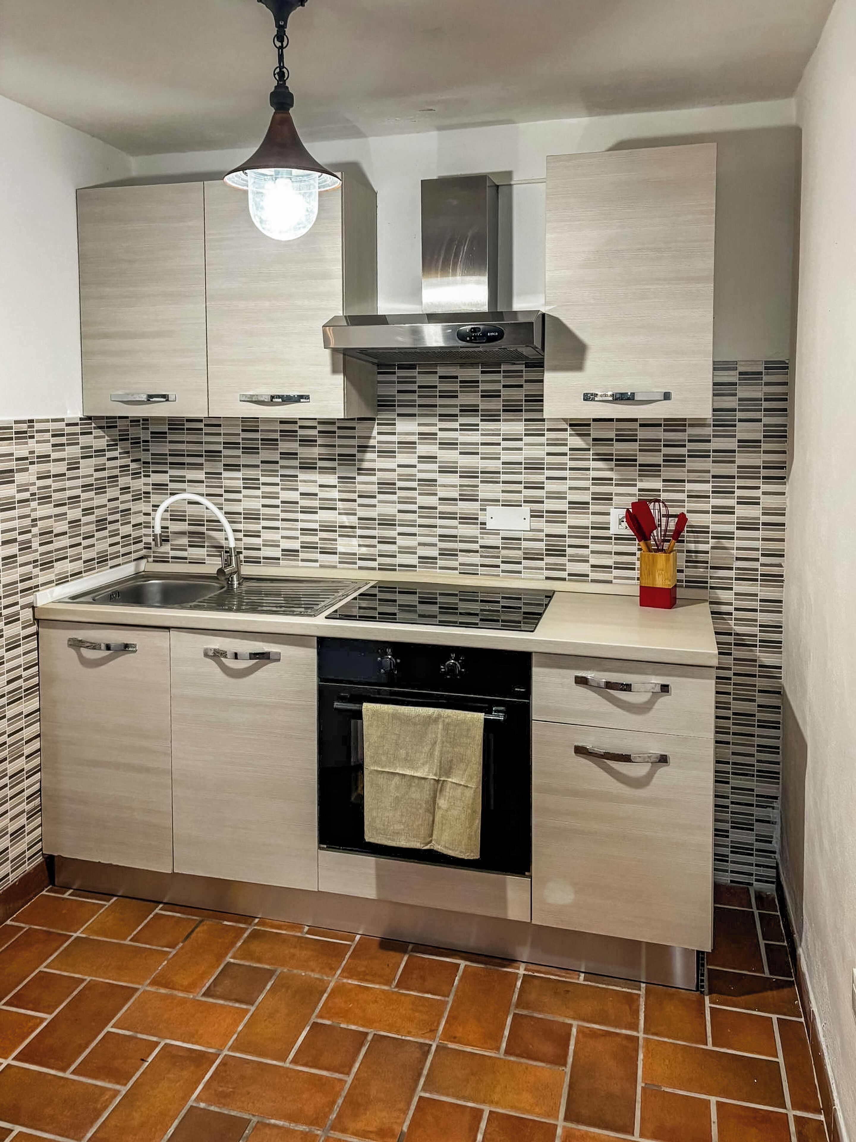 A kitchen with a sink, stove, and cabinets.