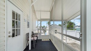 A covered porch with a door, a window, and a row of chairs. - Fish, Boat & Relax-Direct Access Canal Home Near Top Fishing Spots (Punta Gorda)