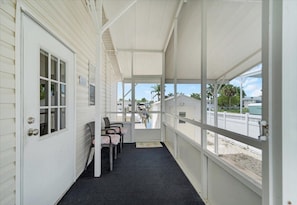 A covered porch with a door, a window, and a row of chairs. - Fish, Boat & Relax-Direct Access Canal Home Near Top Fishing Spots (Punta Gorda)