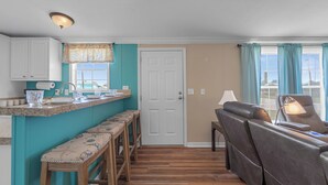 A compact living space with a kitchen area, a seating area with a sofa and chairs, and a door leading to another room. - Fish, Boat & Relax-Direct Access Canal Home Near Top Fishing Spots (Punta Gorda)