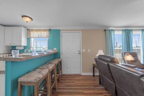 A compact living space with a kitchen area, a seating area with a sofa and chairs, and a door leading to another room. - Fish, Boat & Relax-Direct Access Canal Home Near Top Fishing Spots (Punta Gorda)