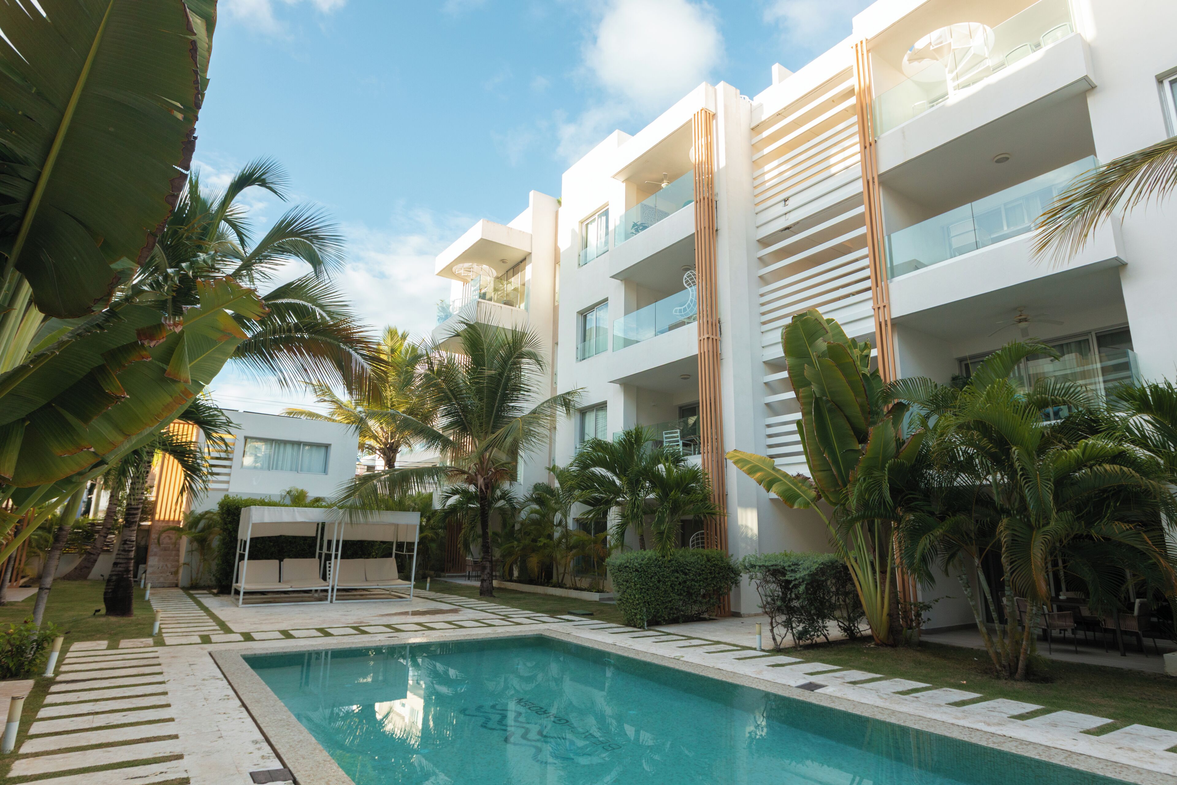 Un hotel moderno con piscina, palmeras y cielo despejado.
