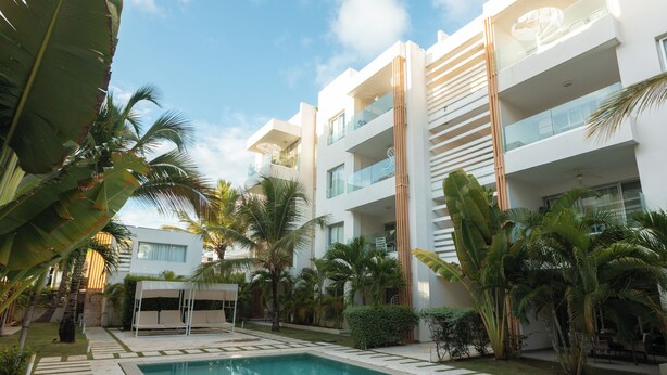 Un hotel moderno con piscina, palme e cielo sereno.