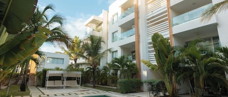 Un hotel moderno con piscina, palmeras y cielo despejado.