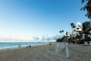 A beach with palm trees, a sandy shore, and a few people. - Pool View and 2 min from the beach: Condo in El Cortecito (Punta Cana)