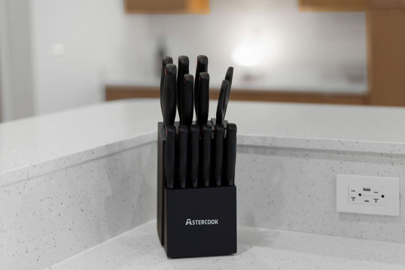 A kitchen counter with a black knife block labeled 'STERCOOK' containing multiple knives.