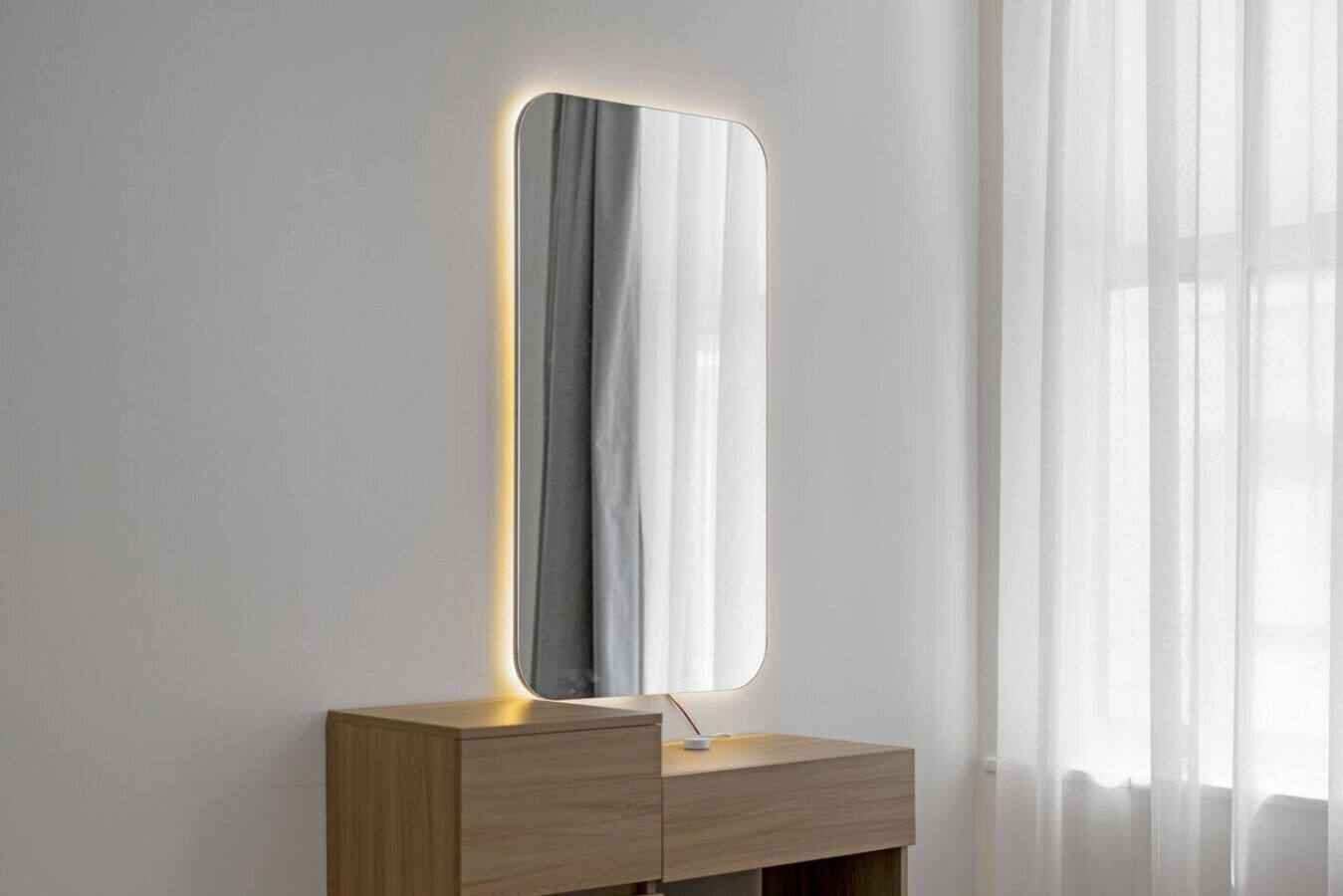 A mirror with a lighted frame on a wooden vanity.
