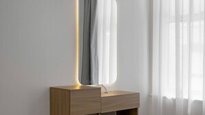 Un miroir avec un cadre illuminé, posé sur une coiffeuse en bois.