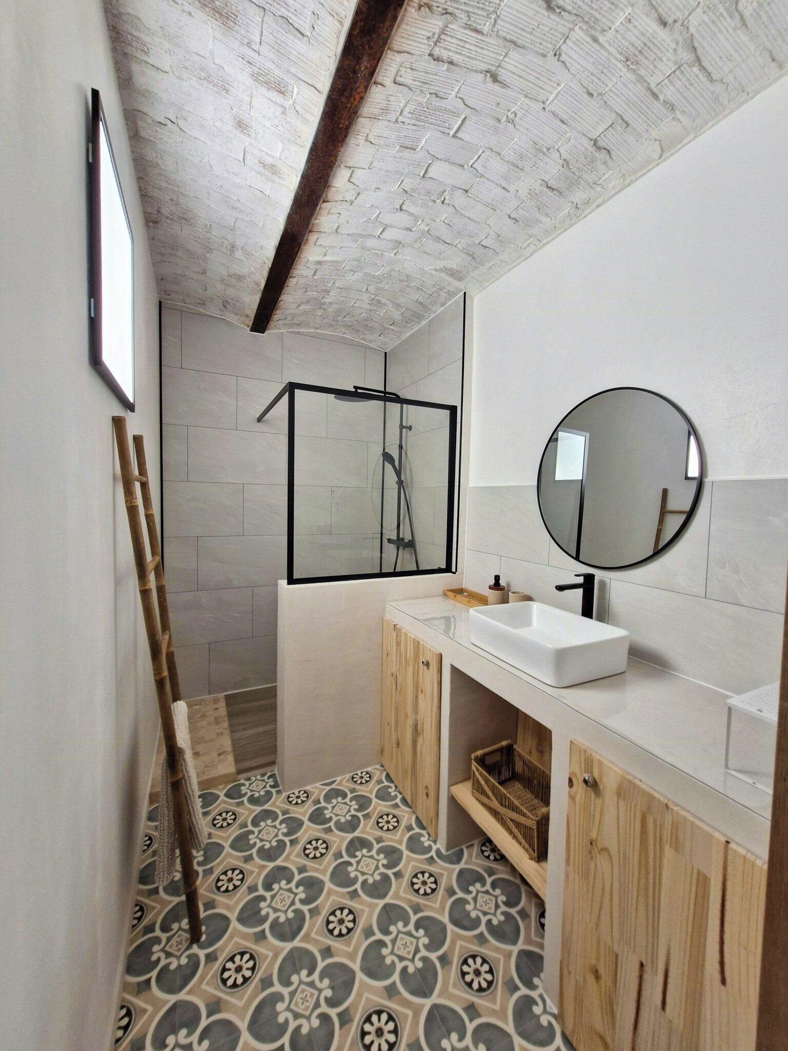 Ein Badezimmer mit Dusche, Waschbecken, Spiegel und fliesenbelagtem Boden.