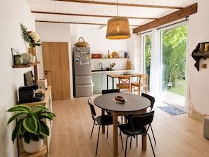 A modern kitchen with a dining area, wooden ceiling beams, and a large window. - Stone farmhouse near Grignan château in Drôme (Roynac)