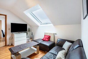 Un salon moderne doté d’une verrière, d’un téléviseur à écran plat, d’un canapé, d’une table basse et d’un meuble blanc.