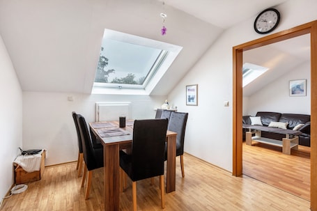 A dining area with a skylight, wooden table, black chairs, and a view of a living room.. Dog-Friendly 4-Room Apartment with Mountain View, Balcony – Near Swiss Border