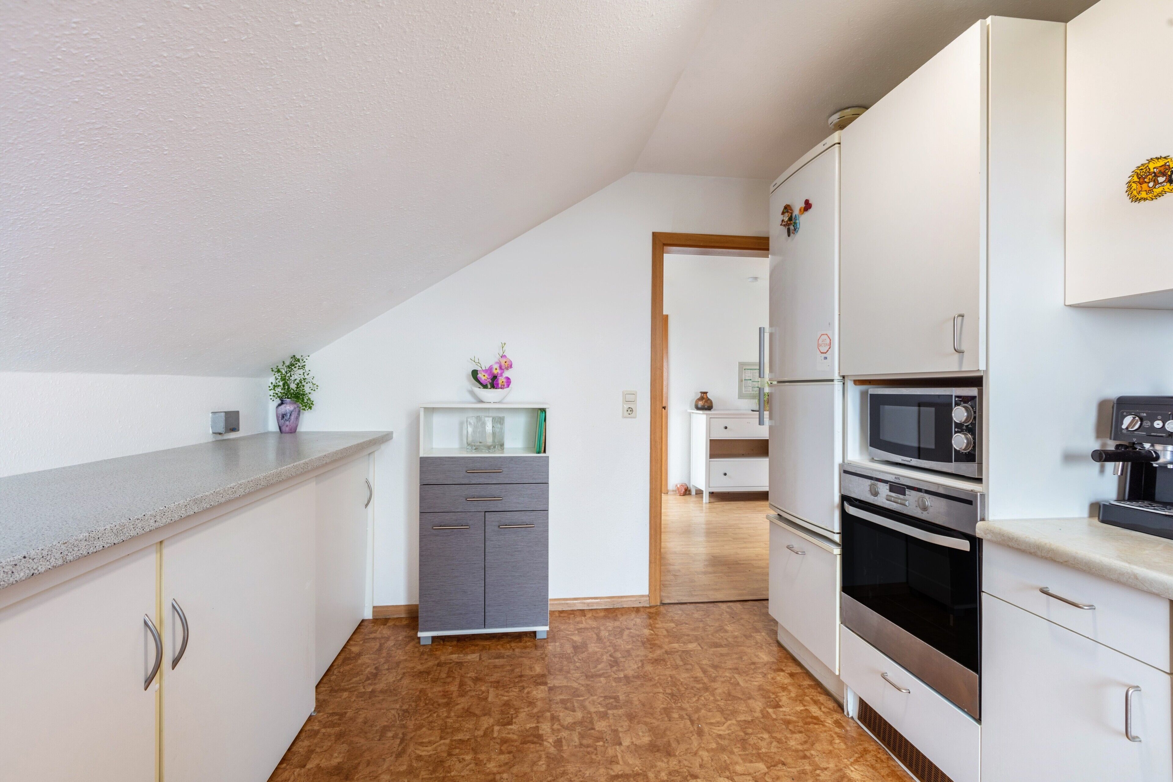 Una cocina con armarios blancos, microondas, horno y encimera.