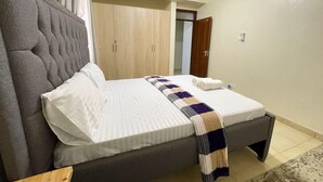A bedroom with a bed, a wardrobe, and a door. - JB VACATION HOME (Mombasa)