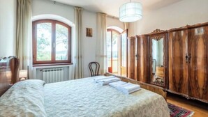 Ein Schlafzimmer mit einem Bett, einem Holzschrank, einem Fenster mit Vorhängen und einer Heizung.