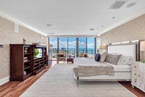 A bedroom with a bed, a nightstand, a dresser, a bookshelf, and a balcony with a view of the sea. - 🐬Top Floor🌞Incredible Water Views🌴Huge Private Balcony🐠Beachfront Community (Treasure Island)
