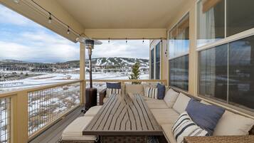 A covered outdoor seating area with a table and chairs, overlooking a snowy landscape.