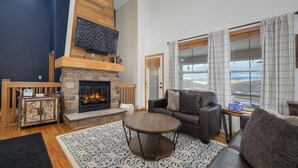Una sala de estar con chimenea, un sofá, una mesa de centro y vistas al exterior.