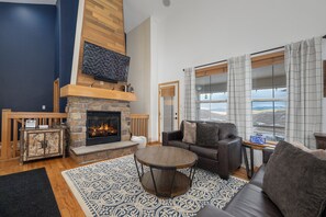 Una sala de estar con chimenea, un sofá, una mesa de centro y vistas al exterior.