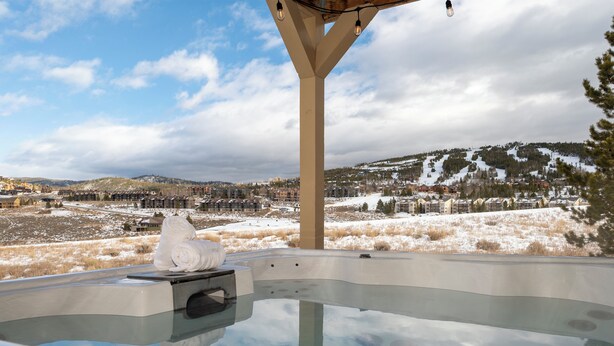 Un jacuzzi con vistas a un paisaje nevado y montañas.