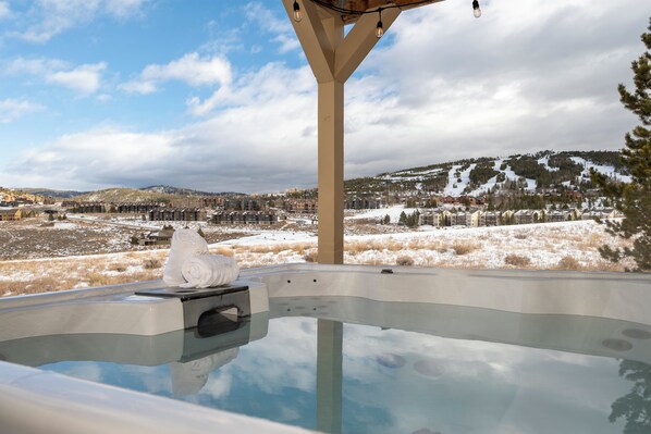 Un jacuzzi con vistas a un paisaje nevado y montañas.