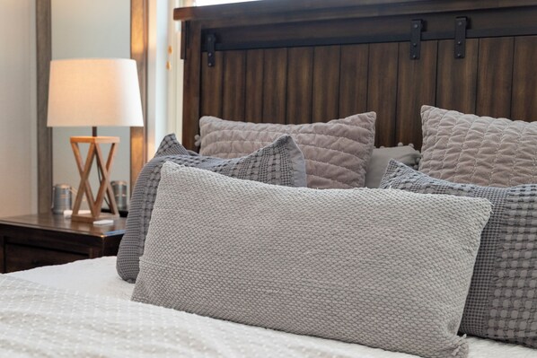 A bed with a quilted headboard, a bedside lamp, and a wooden nightstand with a lamp.