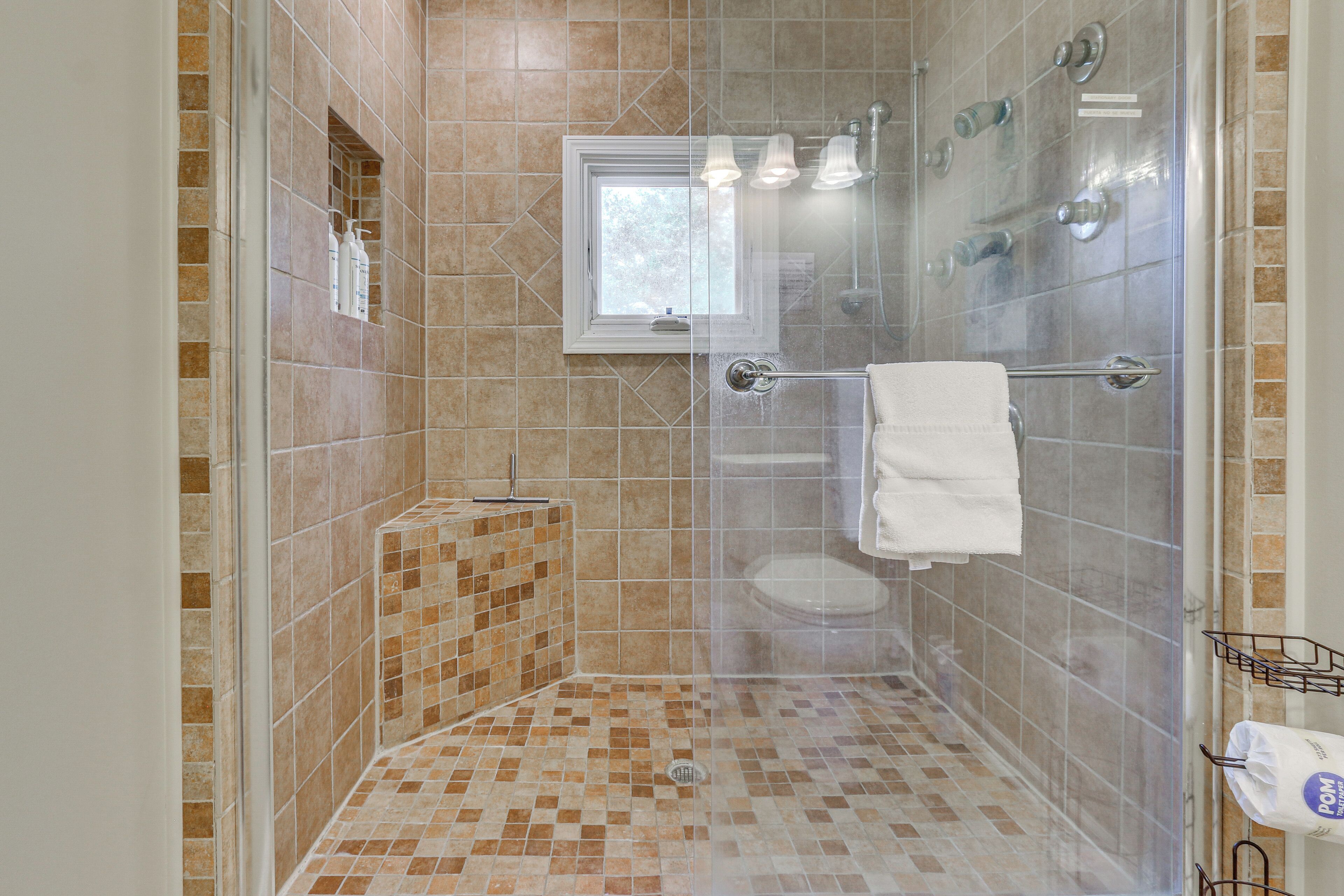 A shower with a glass door, a window, and a towel rack.