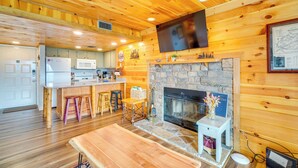 A wooden interior with a kitchen, dining area, and fireplace. - Whispering Woods: Smoky Mountain Resort Escape (Gatlinburg)