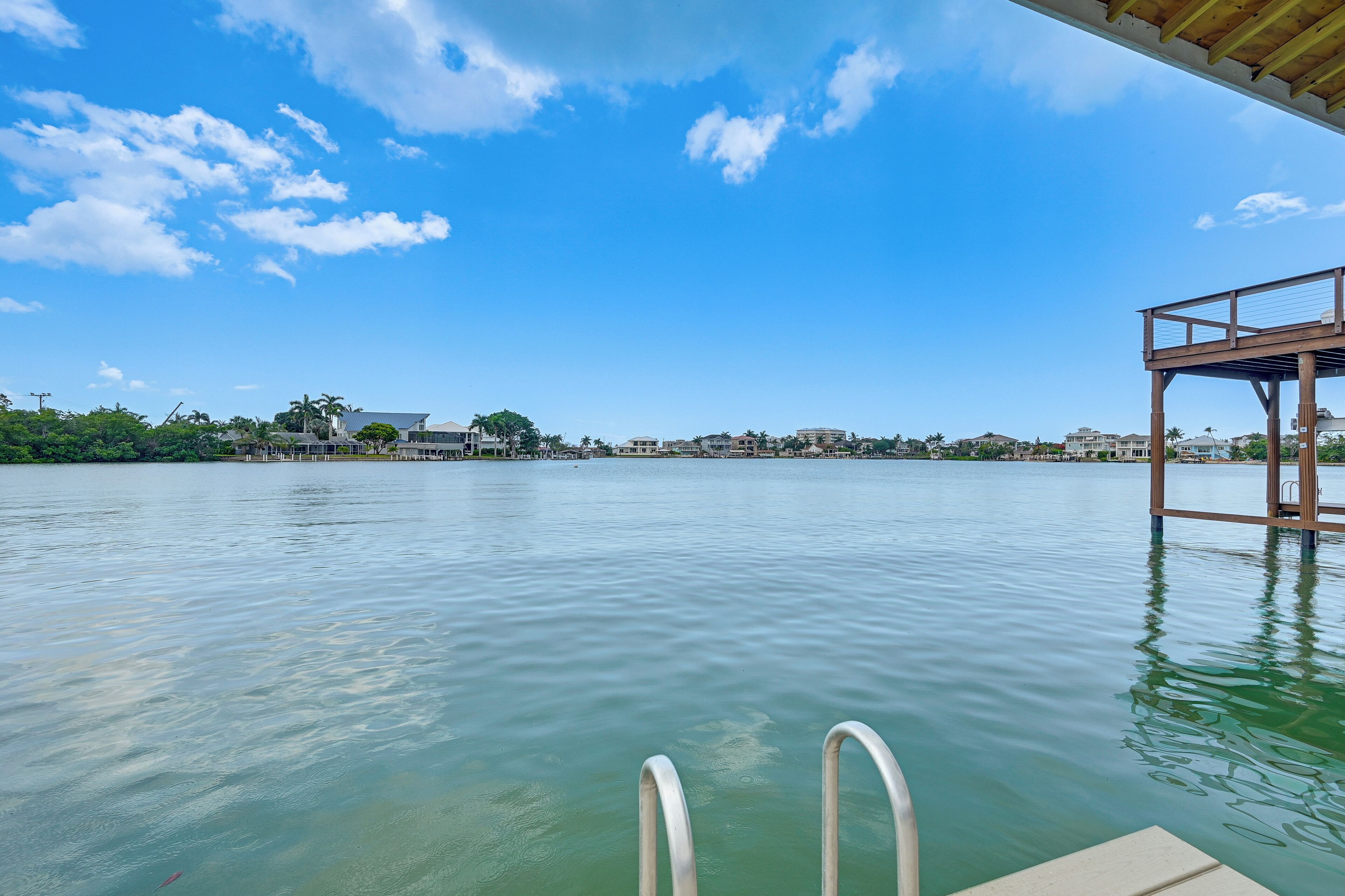 Vista al agua con muelle de madera y piscina.