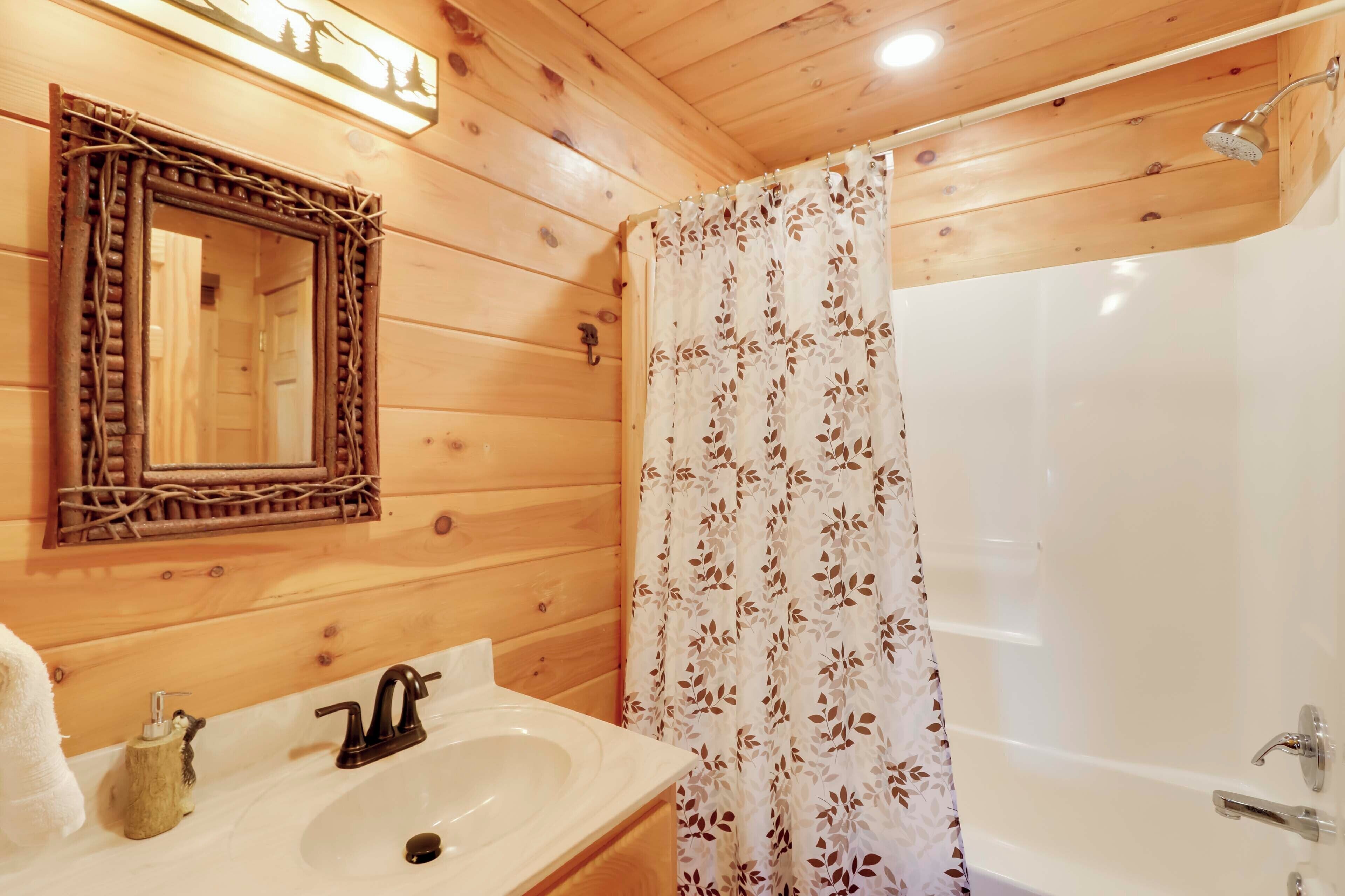 Un baño rústico con cabaña, con un espejo de marco de madera, un lavamanos con grifo, una cortina de ducha y un cabezal de ducha.