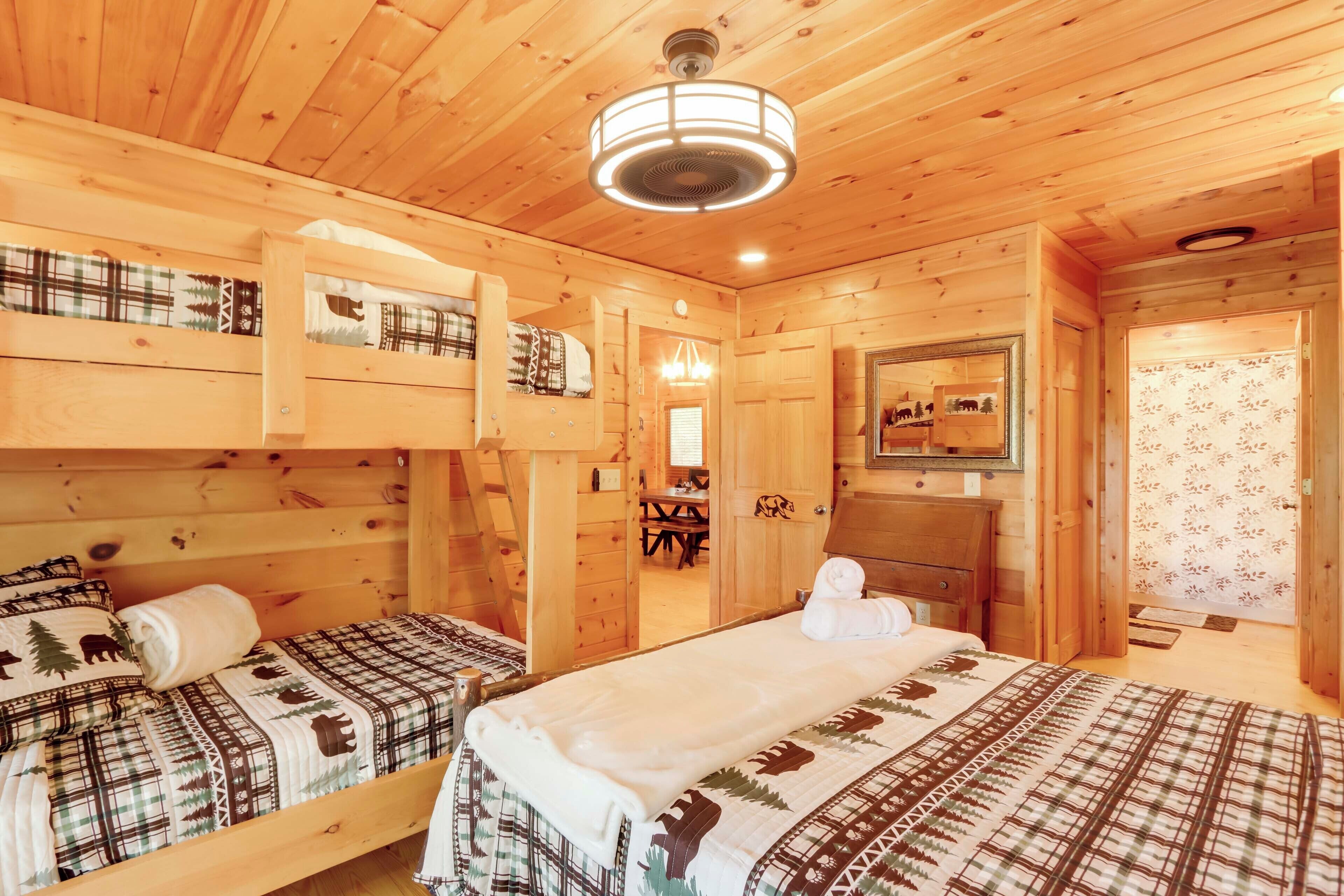 A wooden cabin with two beds, a ceiling fan, a mirror, and a small table.