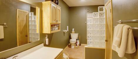 A bathroom with a large mirror, wooden cabinets, a bathtub, a toilet, and a shower area.