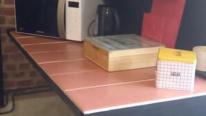 Una cocina con microondas, un armario rojo, una caja de madera y un recipiente para azúcar.