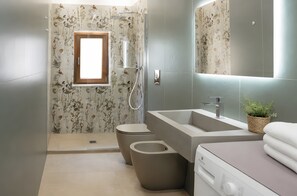 Et moderne badeværelse med bruser, toilet, håndvask og en indbygget vaskemaskine.