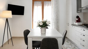 Una cocina moderna con una mesa de comedor, sillas, un televisor y una planta decorativa.