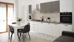Una cocina moderna con armarios blancos, una mesa de comedor con sillas, una estufa y un horno empotrado.