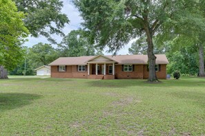 A single-story brick house with a front porch, a garage, and a well-maintained lawn.