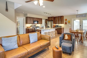 Una cocina moderna con armarios de madera, una isla central y un comedor con mesa y sillas de madera.
