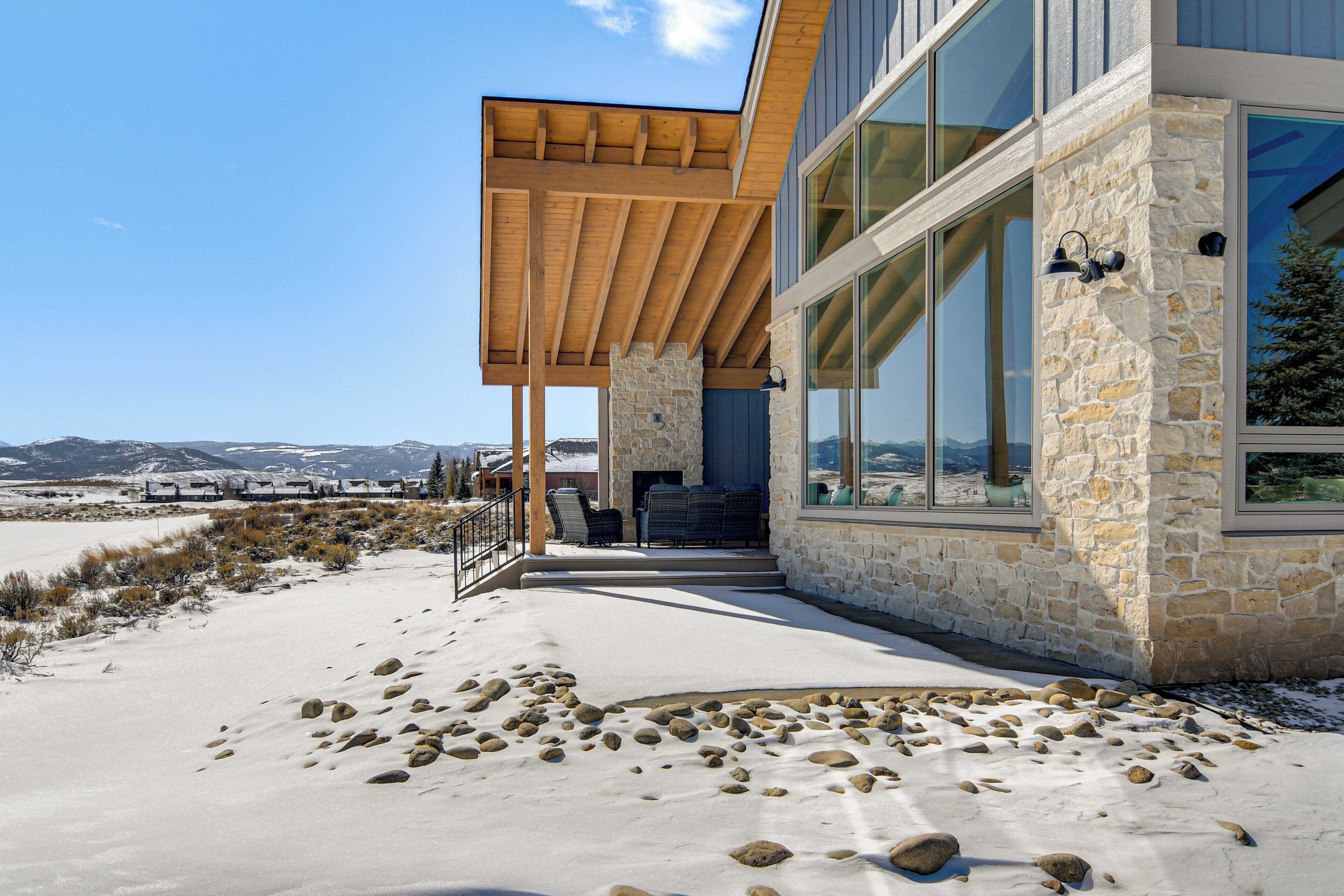 A modern building with large windows, a stone facade, and a wooden pergola.