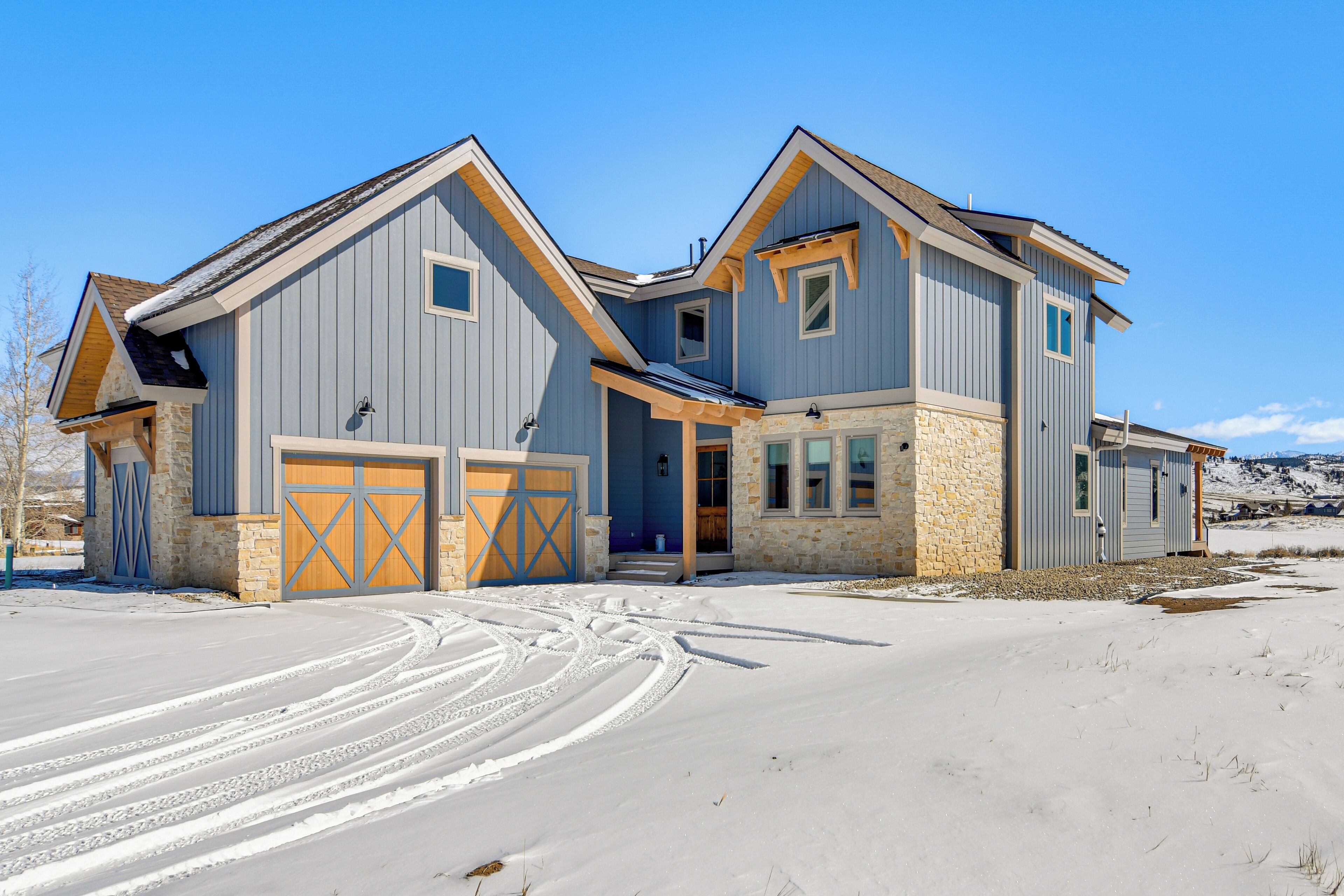 A two-story house with a stone foundation, a garage, and a large driveway.